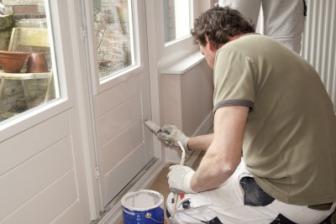 painter white washes an exterior door